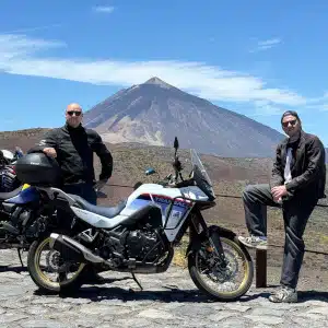 Friends next to a Honda Transalp 750 with Mount Teide in the background in Tenerife.